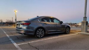 Coche gris aparcado en un terreno baldío.