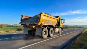 Yellow dump truck driving on highway