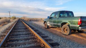 Green truck parked beside railroad tracks