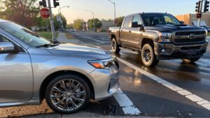 Silver car and black truck at intersection