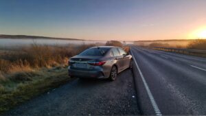 Gray sedan parked by misty road
