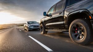 Black truck and gray Tesla driving