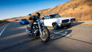 Motorcycle racing alongside classic cars.