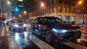 Two cars at a rainy intersection.