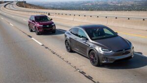 Gray Tesla and red Toyota SUVs driving