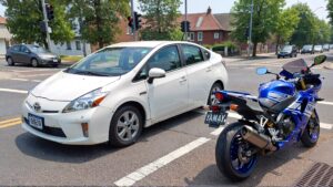 White Prius and blue Yamaha motorcycle.