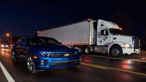 Blue Camaro beside a big rig.