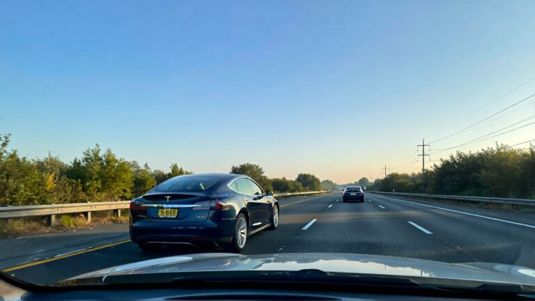 Juris Digital a Telsa and another car on the highway in the morning 35337a49 5280 454f 8fe3 fe885e32a730 1