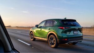 Green Mazda CX-50 driving at dawn