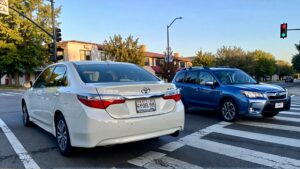 White Toyota and blue Subaru parked.