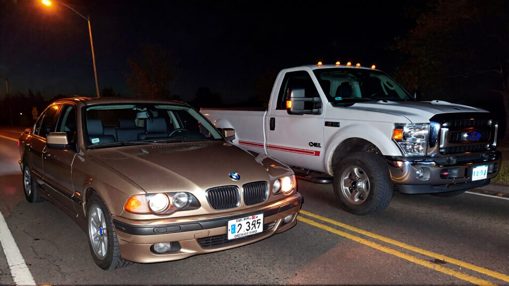 Juris digital an older BMW sedan and a Ford F250 pickup truck on the road at ni 5b227645 c32f 4df2 9951 8c7e5459ad67