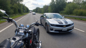 Motorcycle beside Chevrolet Camaro on highway
