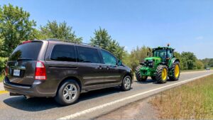 Minivan and tractor on the road.