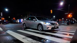 Silver sedan in crosswalk at night