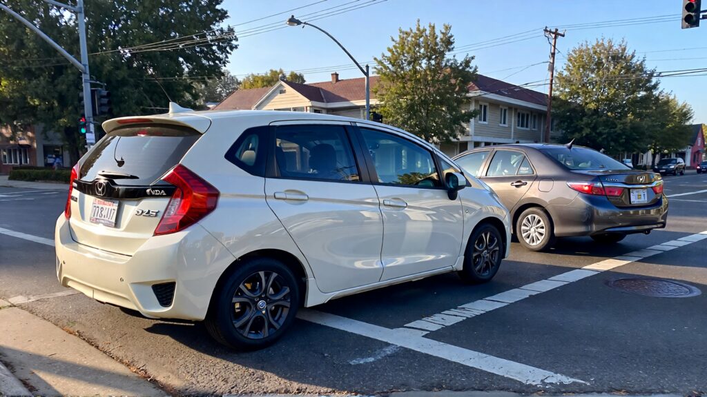 Samantha parian A white Honda Fit and a gray Toyota Camry in a street intersectio 53d65a69 9776 4333 a696 4e2d07a8dc40