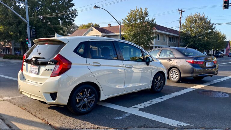 Two cars at a street intersection.
