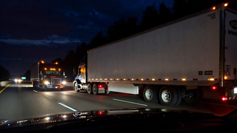 Two trucks on a dark highway