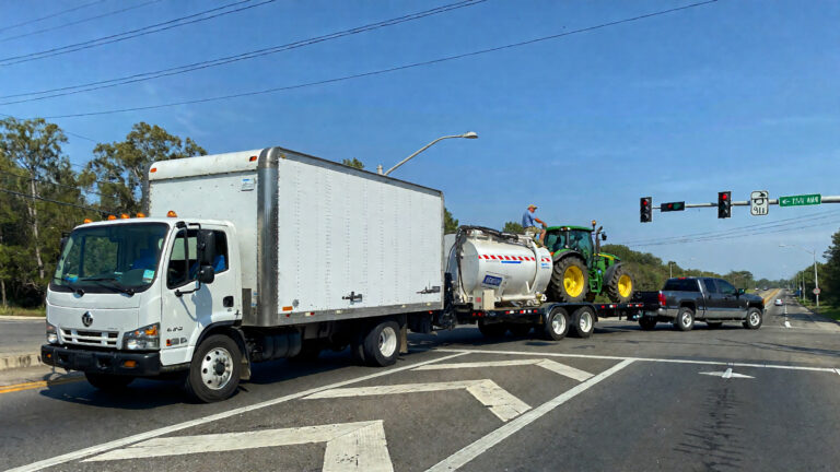 Trucks and tractor at traffic signal.