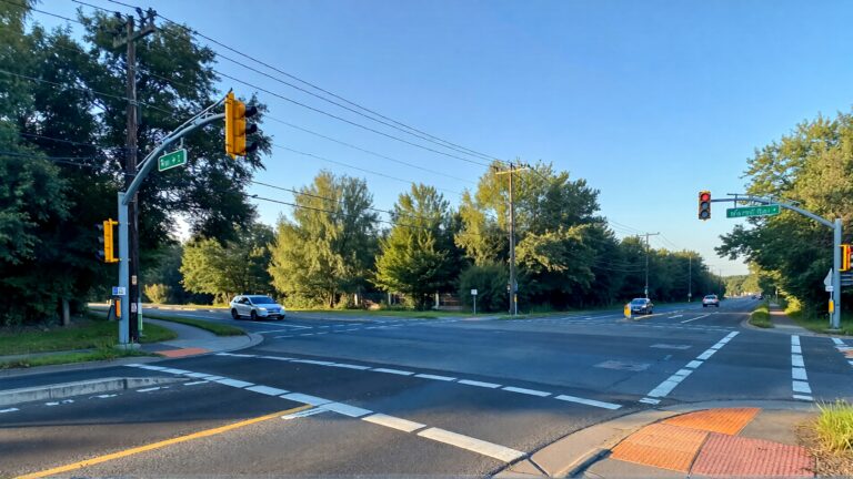 Sunny road intersection with traffic signals.