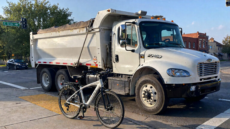 Dump truck parked beside an e-bike.
