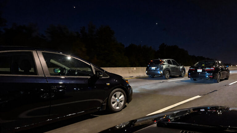 Three cars on a dark highway.