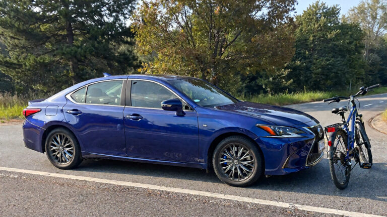 Blue sedan parked beside a bicycle.