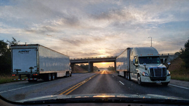 Dos camiones en una autopista al atardecer.