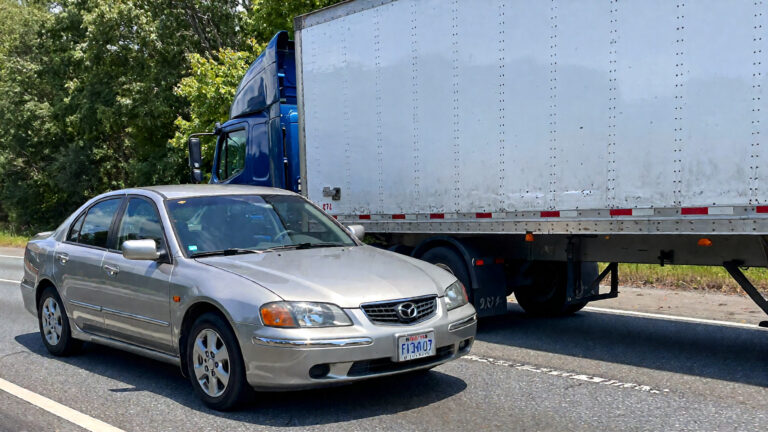 Silver sedan beside large truck