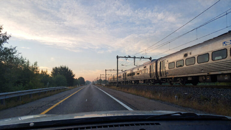 Train passing alongside a quiet road.
