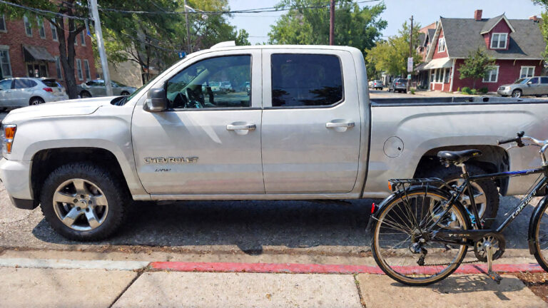 White truck parked beside bicycle.