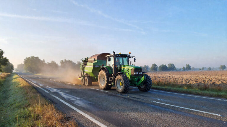 Tractor conduciendo en un camino con neblina.