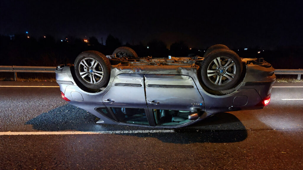 Overturned car on dark highway.